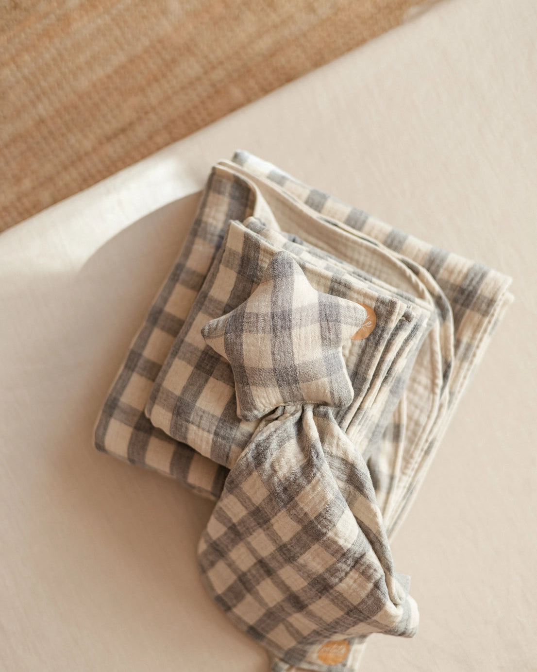 Folded checkered blanket with a star-shaped pillow on a beige surface