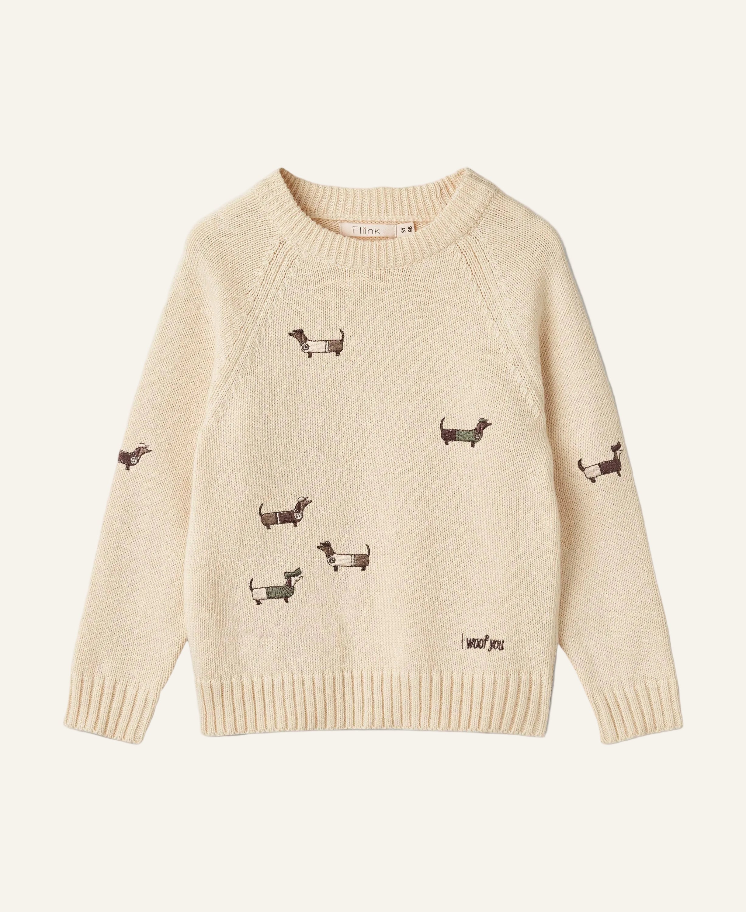 Beige sweater with embroidered dog patterns on a white background