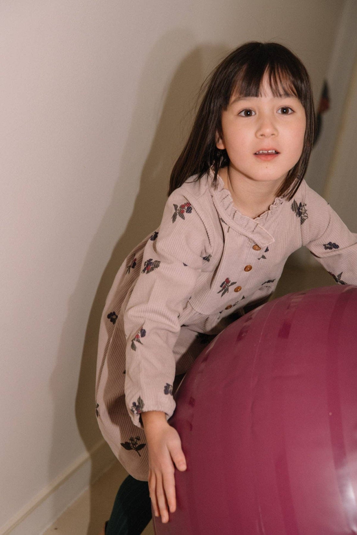 Child playing with a large pink ball indoors