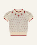 A cream-colored short-sleeve knit sweater with red trim, featuring a pattern of tiny red hearts and three embroidered strawberry motifs on the chest, displayed flat against a light gray background.