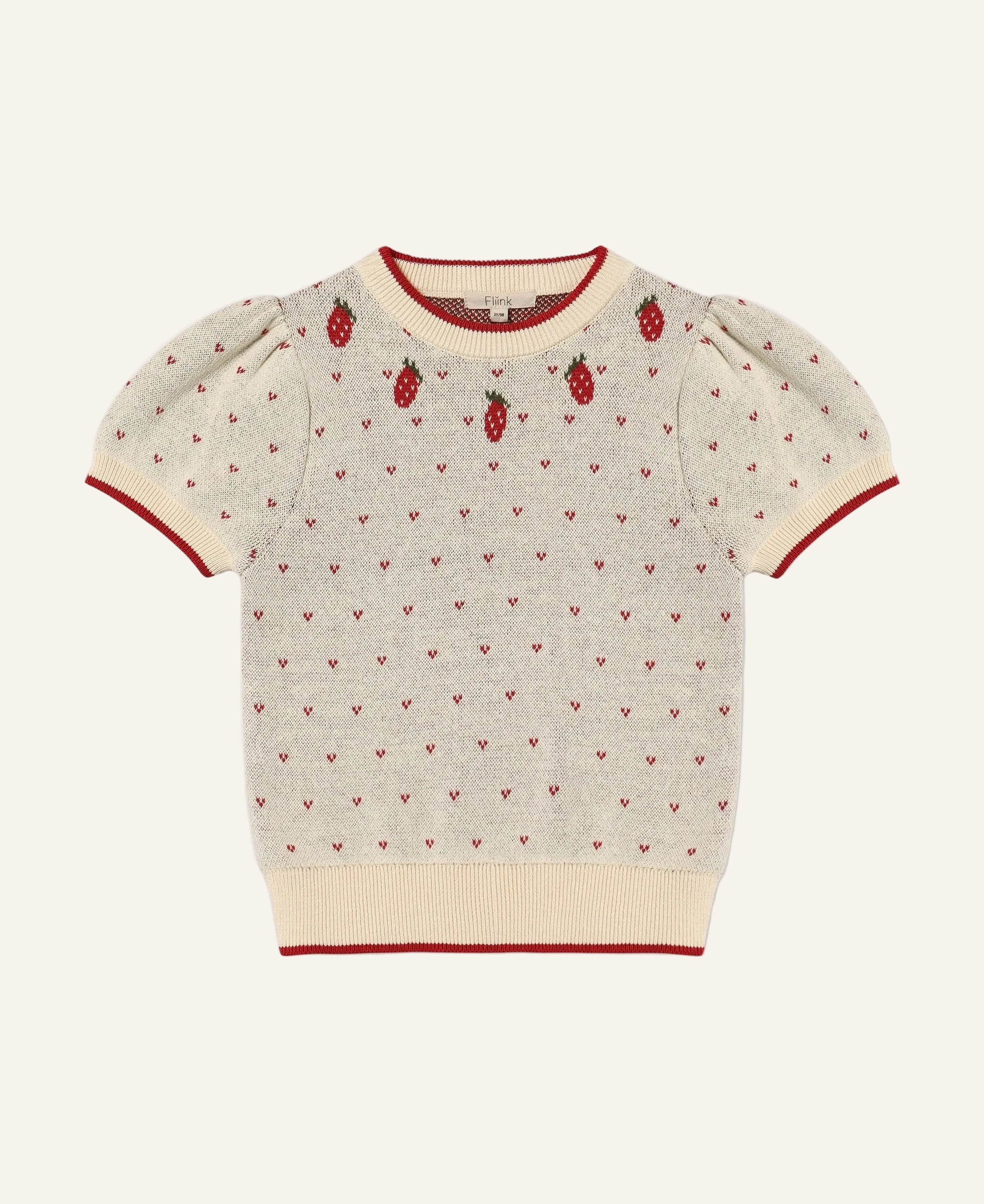 A cream-colored short-sleeve knit sweater with red trim, featuring a pattern of tiny red hearts and three embroidered strawberry motifs on the chest, displayed flat against a light gray background.