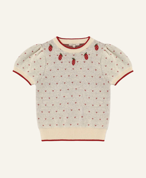 A cream-colored short-sleeve knit sweater with red trim, featuring a pattern of tiny red hearts and three embroidered strawberry motifs on the chest, displayed flat against a light gray background.