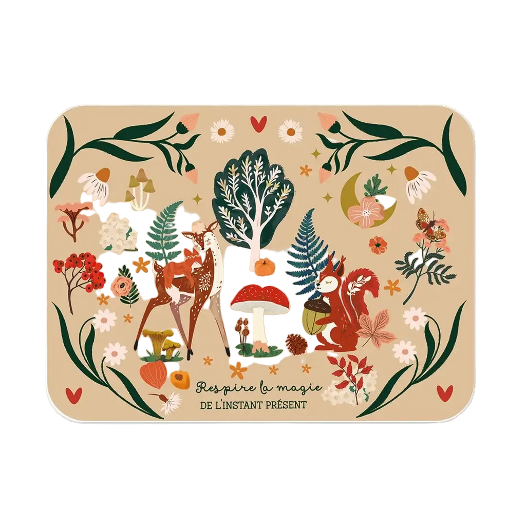 A rectangular mat with rounded corners featuring a whimsical forest illustration in warm autumn tones. The design includes deer, a tree, mushrooms, flowers, leaves, and small woodland motifs on a beige background, with the French text 'Respire la magie DE L'INSTANT PRÉSENT' near the bottom.