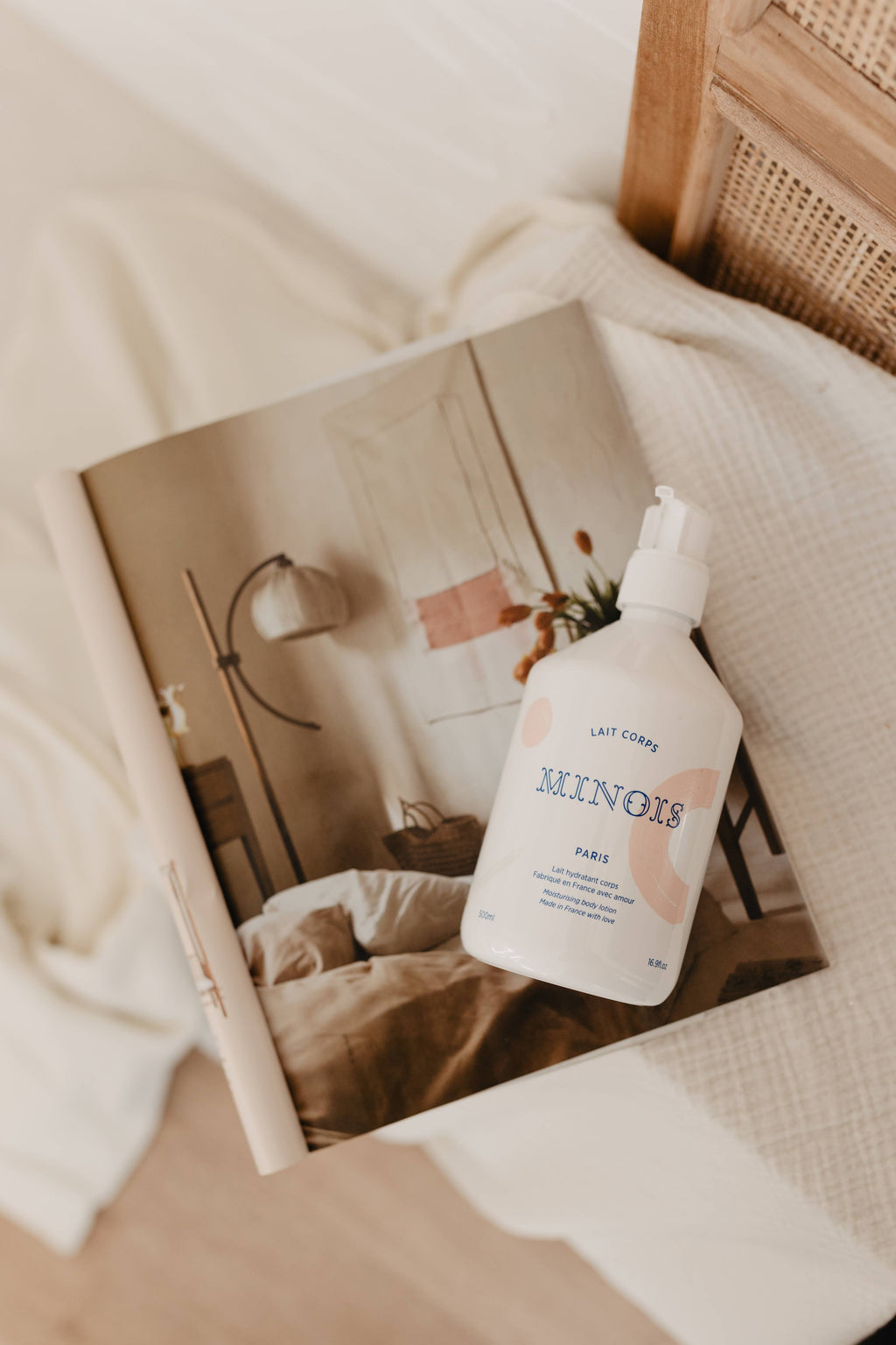 Bottle of Minois baby lotion on a magazine with a blurred indoor background