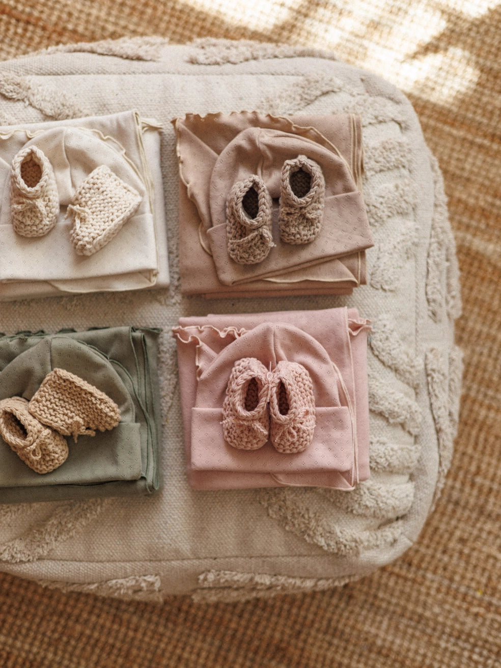 Baby booties and blankets arranged on a textured surface
