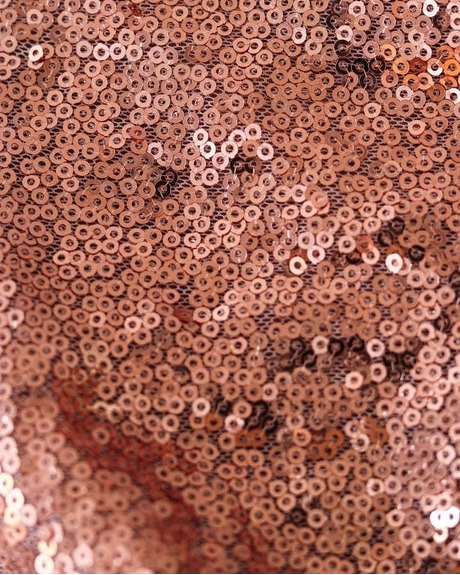 Close-up of a rose gold sequin fabric texture with dense circular sequins reflecting light.