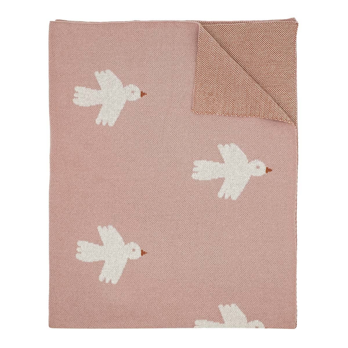 Pink blanket with white bird patterns on a white background