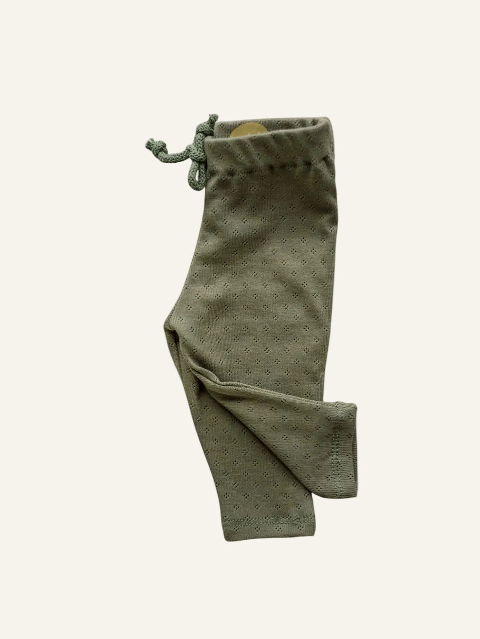 Olive green knit pants with a small repeating geometric pattern, featuring an elastic drawstring waist and ribbed ankle cuffs, shown against a plain white background.