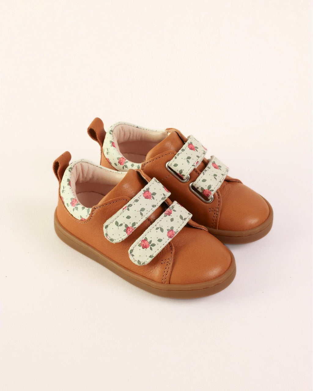 A pair of toddler's brown leather shoes with floral-patterned velcro straps, shown on a plain light background.