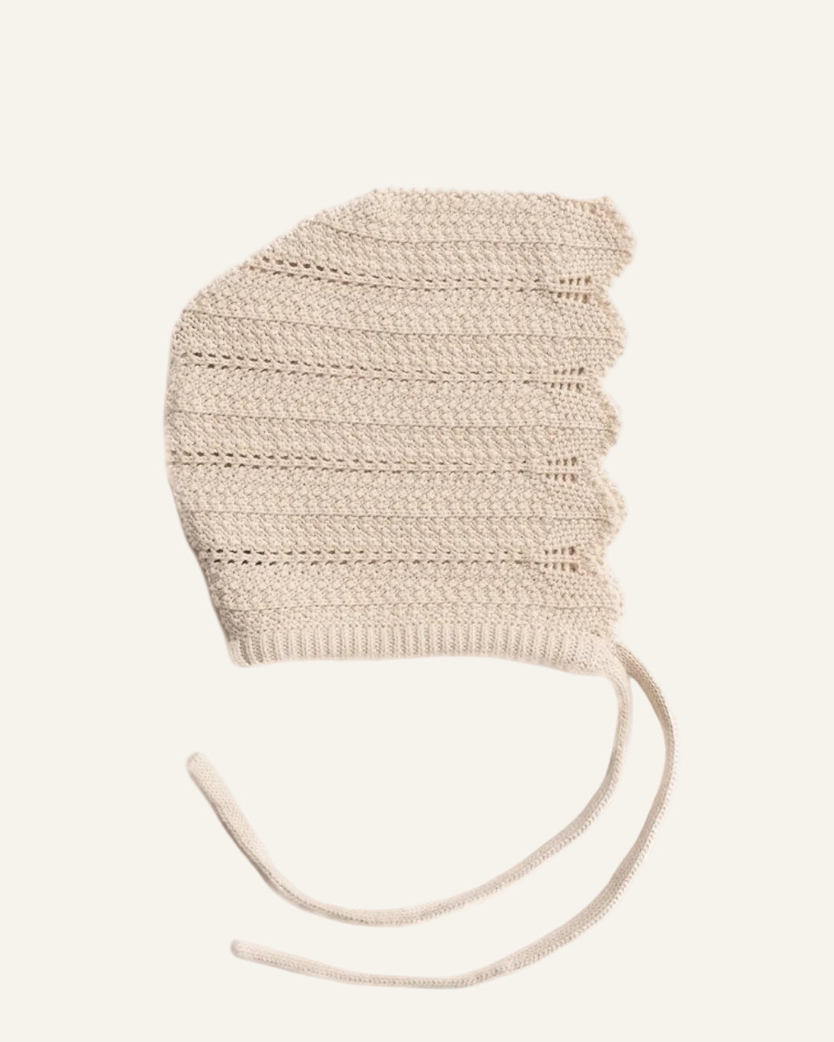 Knitted beige baby bonnet on a white background