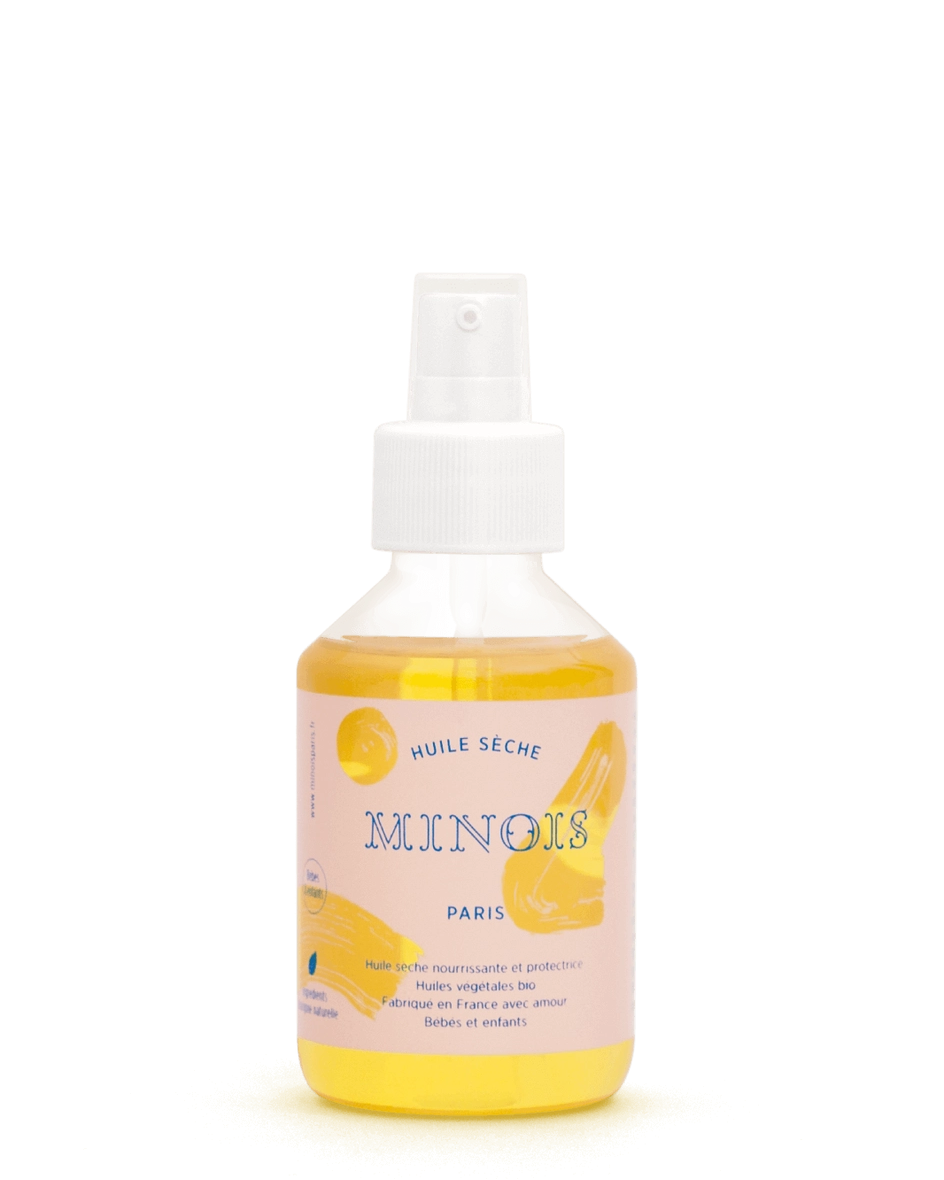 A spray bottle of Mingois Paris dry skin oil with a white pump dispenser, featuring a pastel pink label with yellow citrus graphics and French text, set against a plain white background.