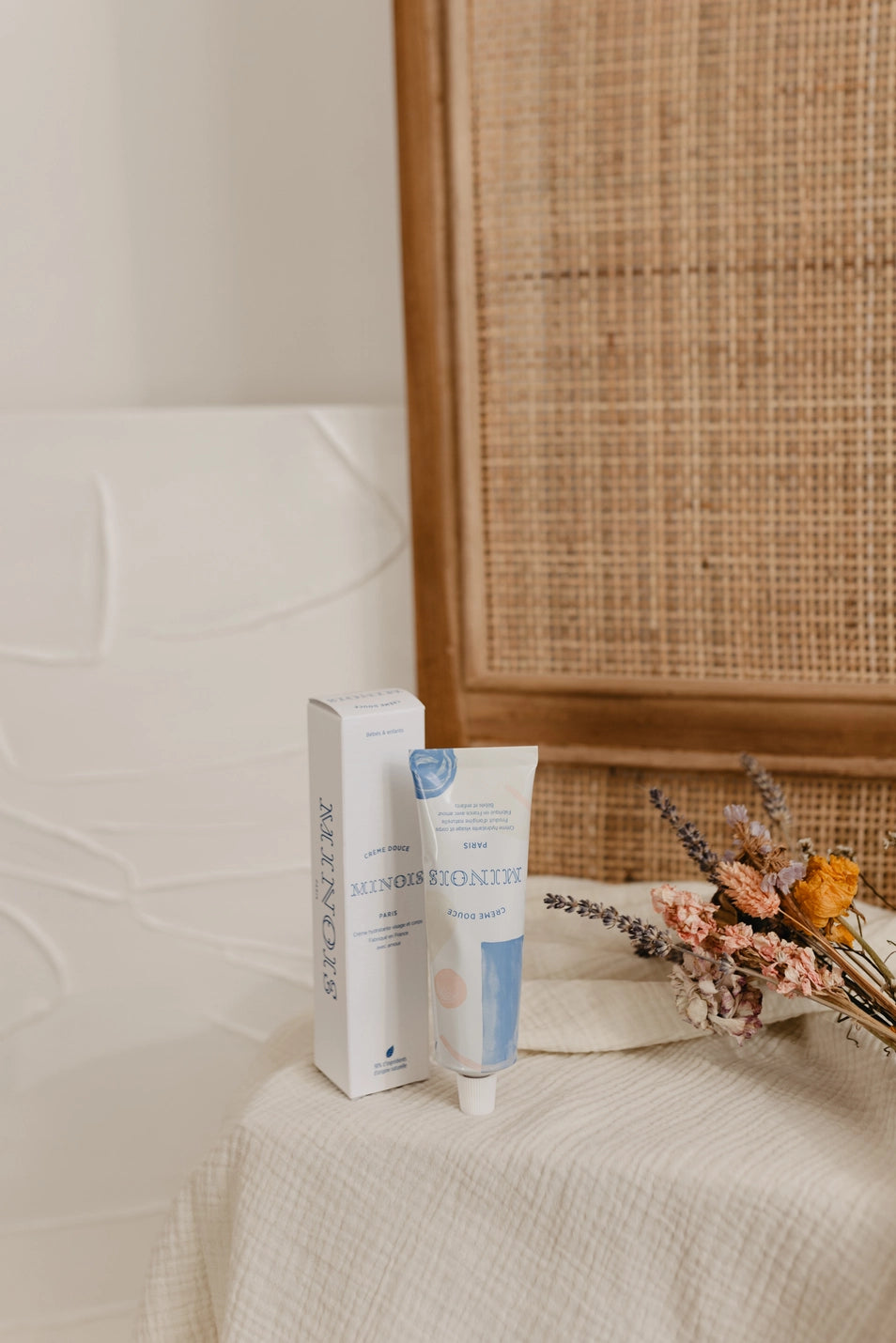 Skincare product and packaging on a textured surface with a woven wall in the background
