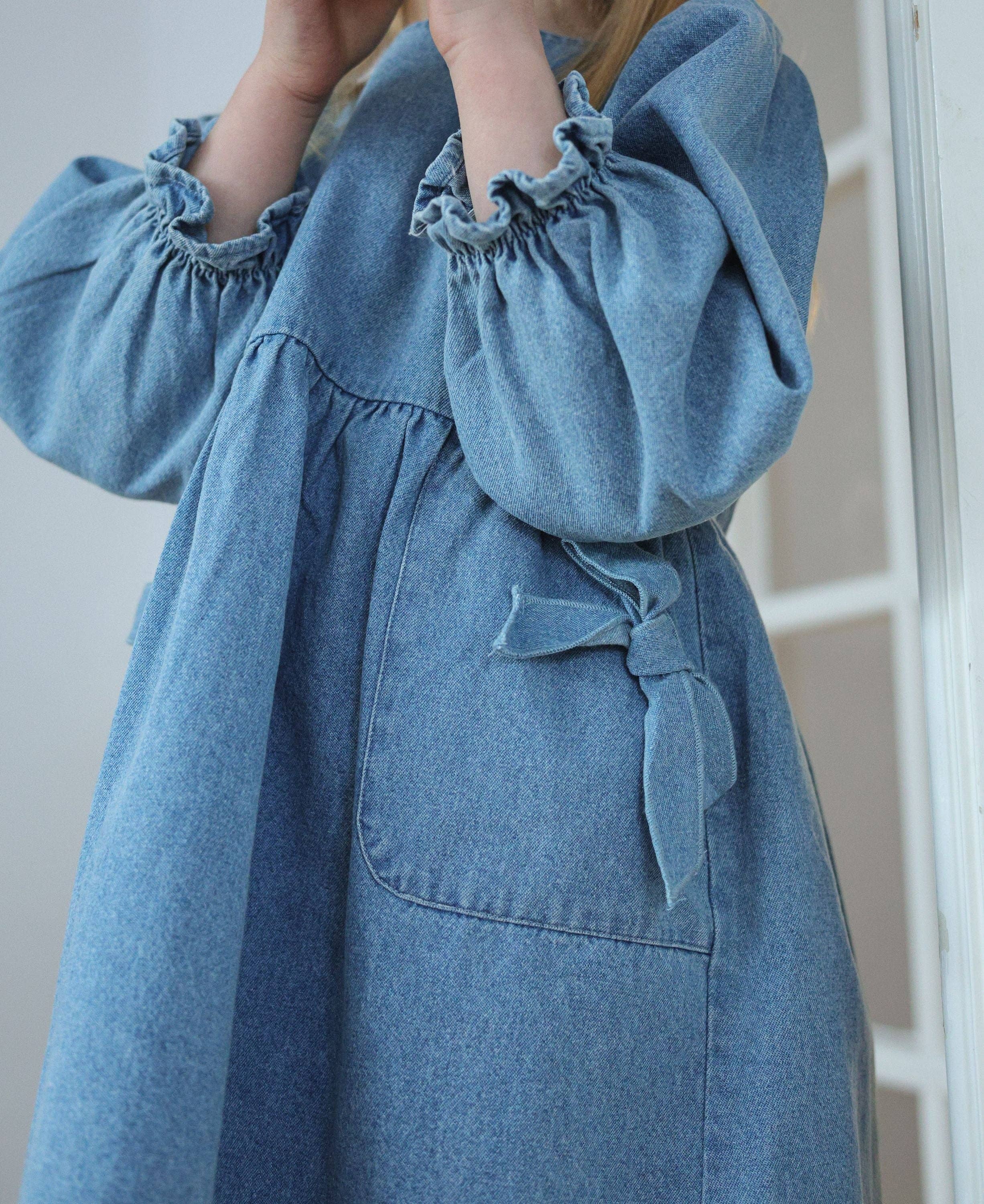 Blue denim dress with ruffled sleeves and a tie detail.