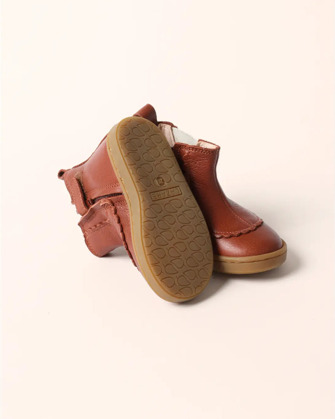 A pair of brown leather ankle boots with a textured sole, shown from a top-down angle on a light cream background.