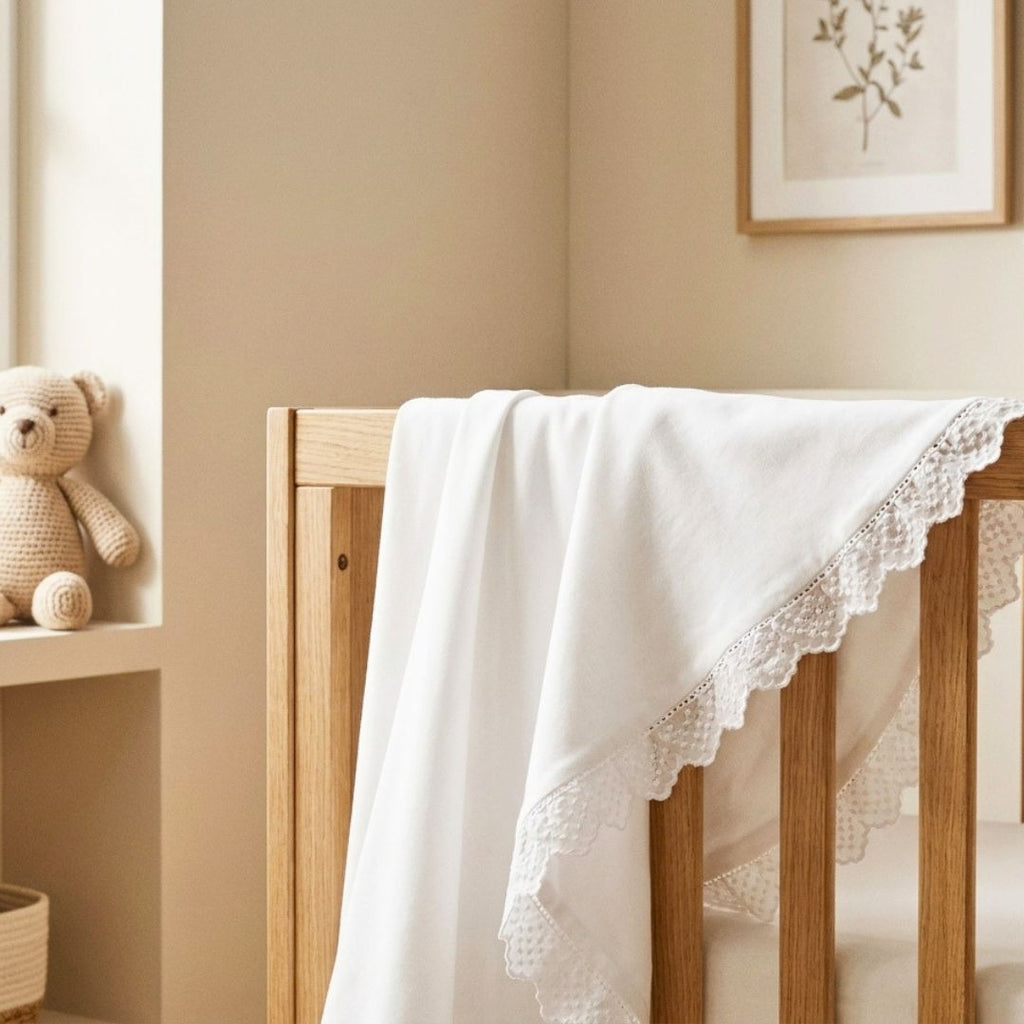 Wooden crib with a white lace blanket draped over it in a nursery setting.
