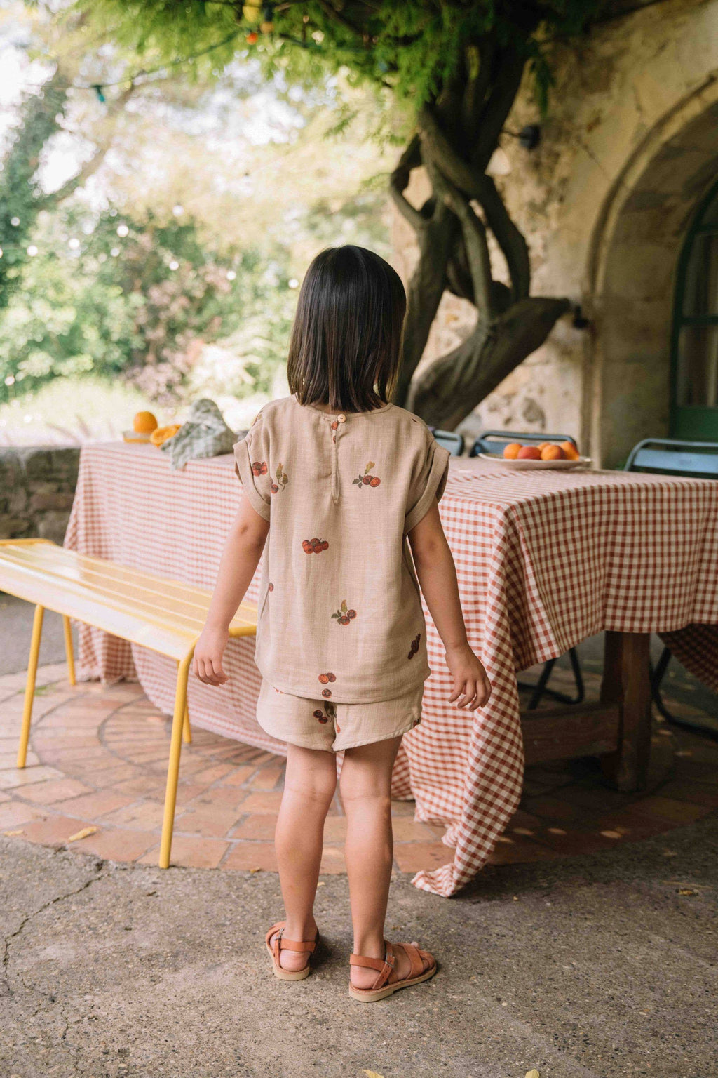 Child standing in front of a table with a checkered tablecloth outdoors