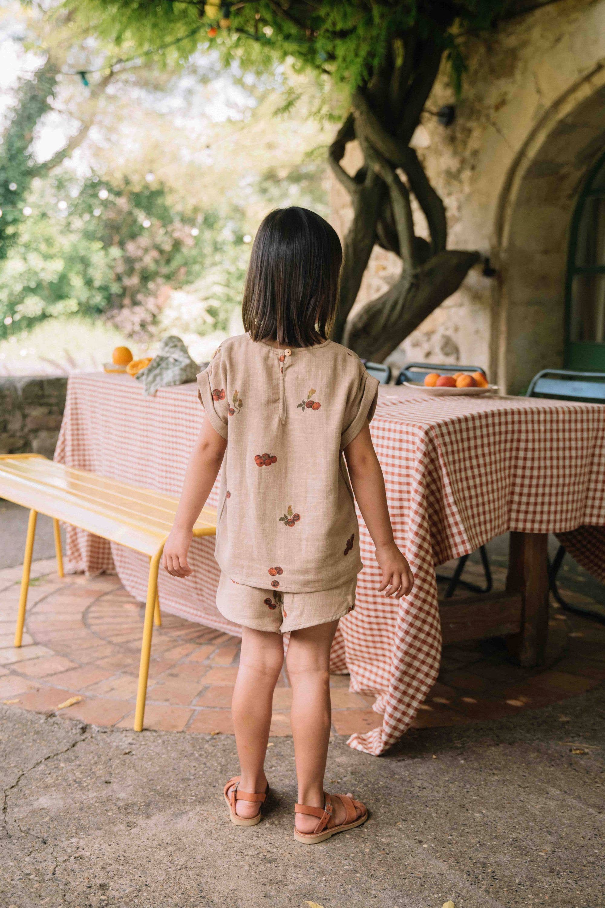 Child standing in front of a table with a checkered tablecloth outdoors