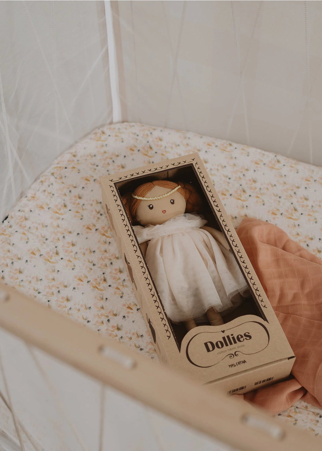 Small doll in a box labeled 'Dollies' held by a hand against a light background