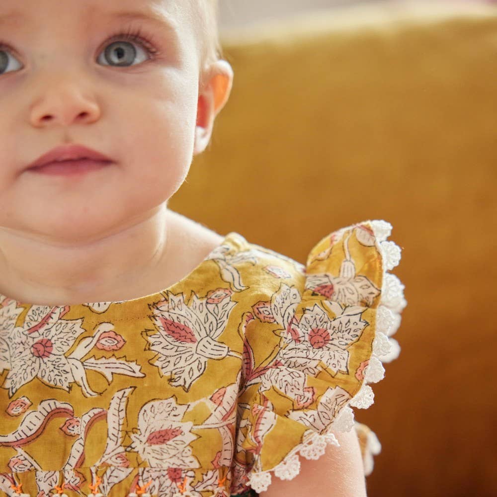 Close-up of a baby wearing a floral dress with a blurred background