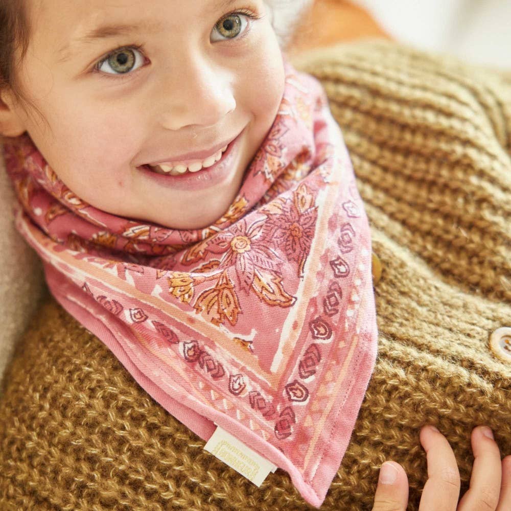 Child wearing a pink patterned scarf with a brown textured sweater