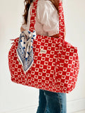 Person holding a red and white patterned bag with a blue bandana