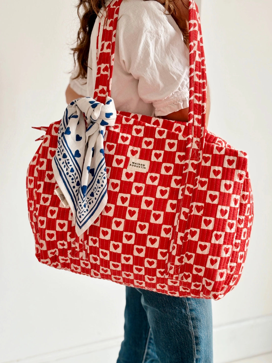 Person holding a red and white patterned bag with a blue bandana