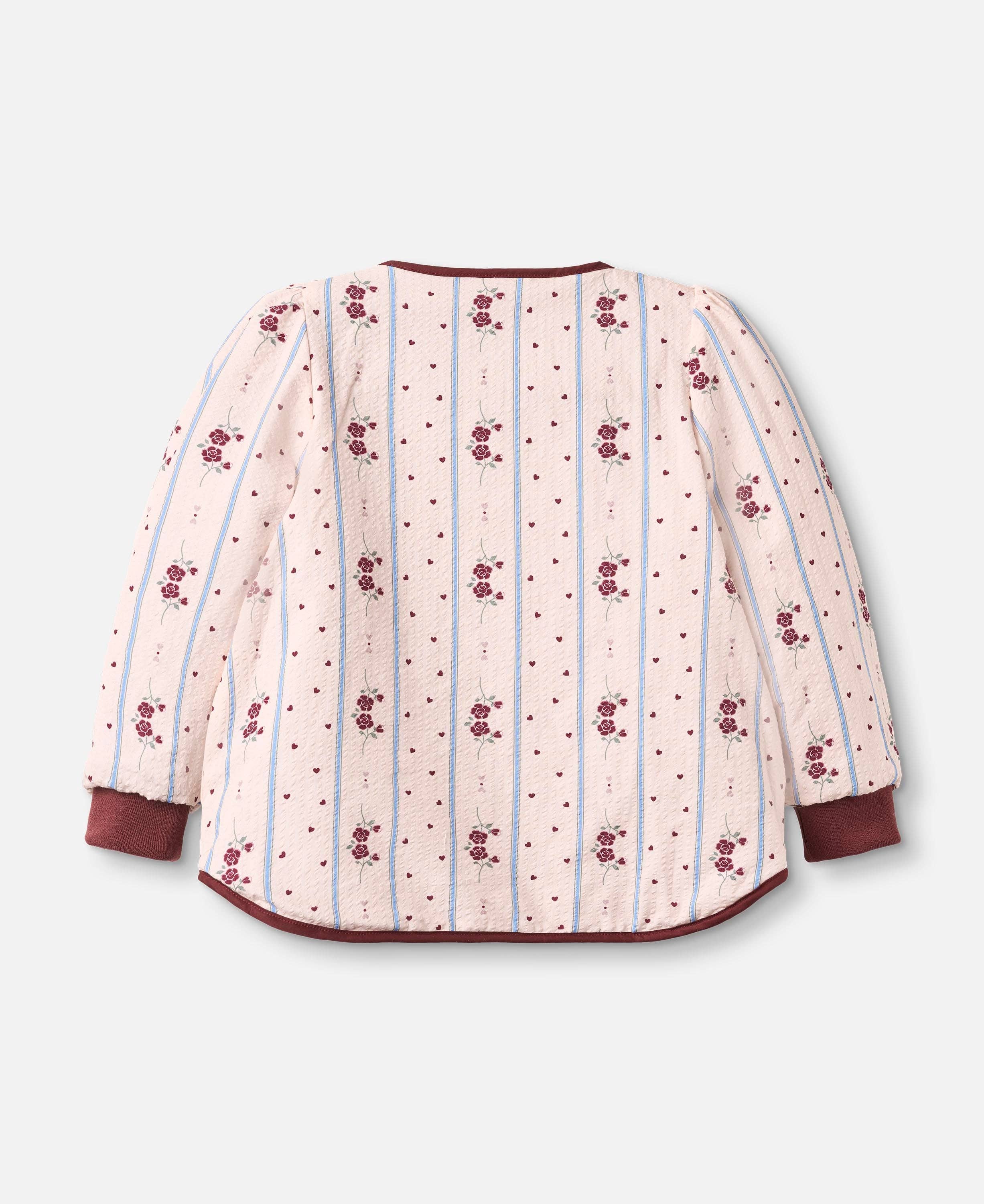A long-sleeve quilted jacket with a cream-colored body, decorated with vertical light blue stripes, small red polka dots, and repeating red floral motifs. It features solid dark red cuffs and a matching dark red curved hem, shown against a light gray background.