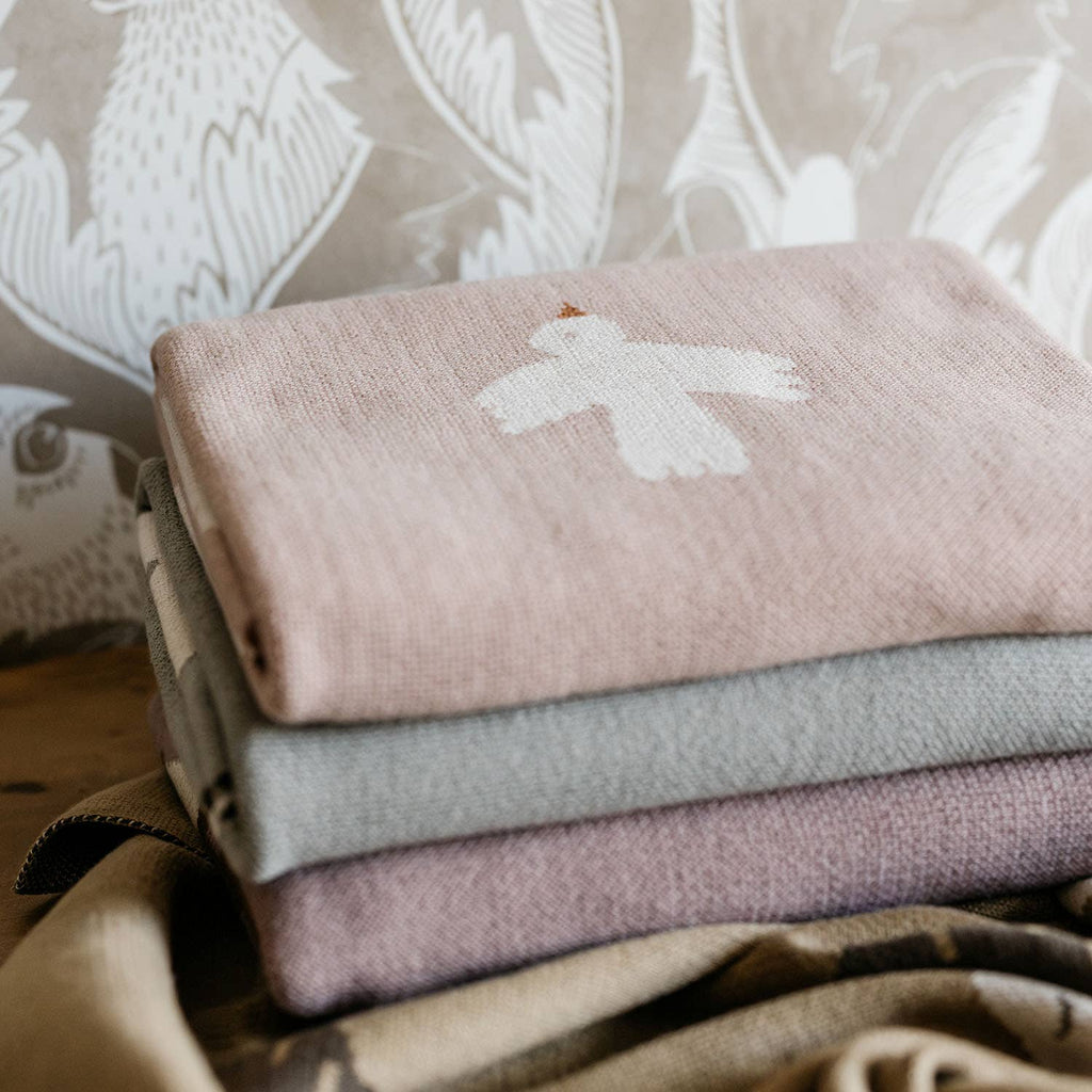 Stack of folded fabric swatches with embroidered patterns on a neutral background