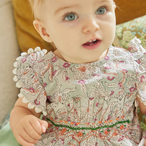 Baby wearing a floral dress with ruffled collar