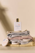 Perfume bottle on a stack of folded clothes with a neutral background