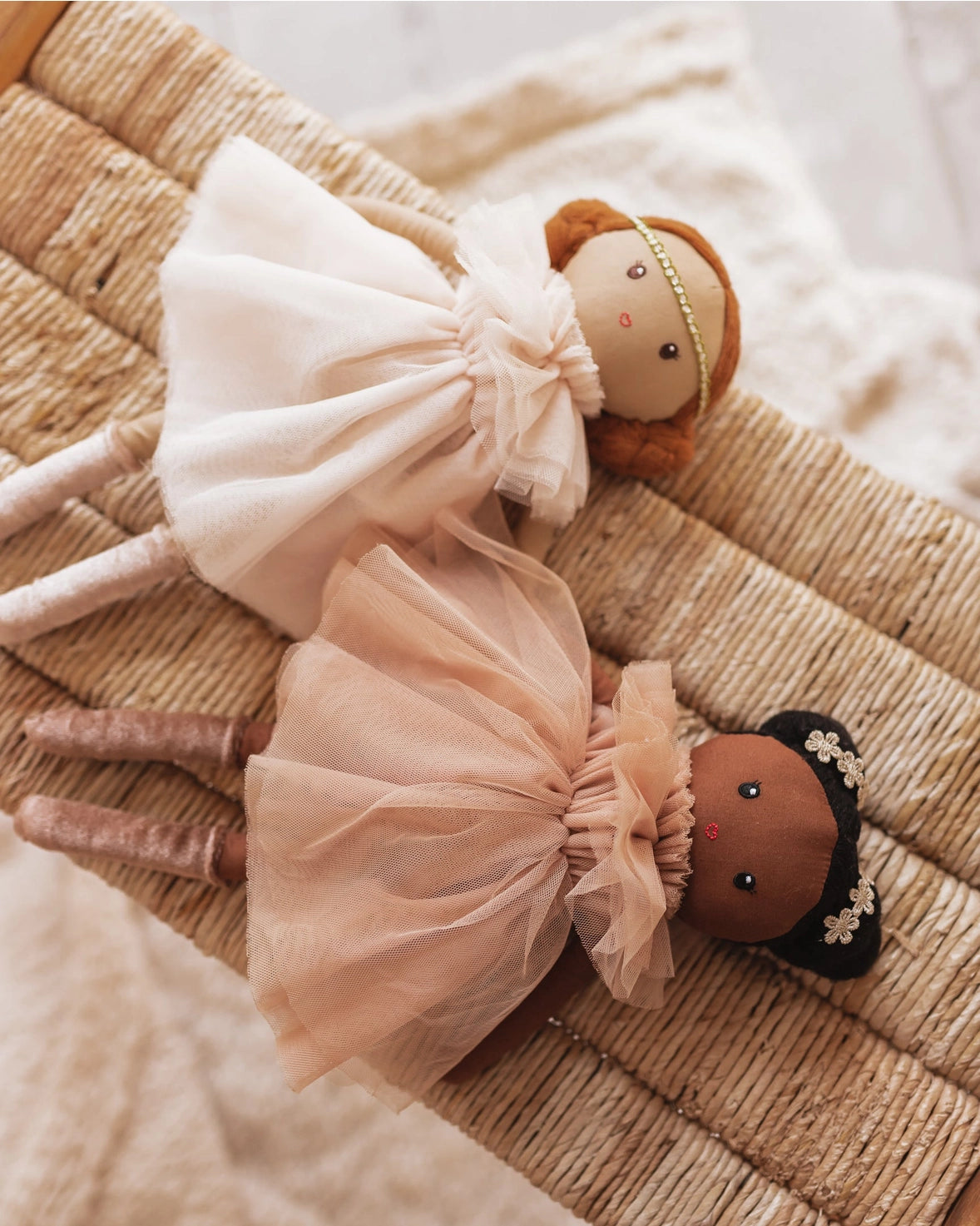 Two dolls with tulle dresses on a textured surface