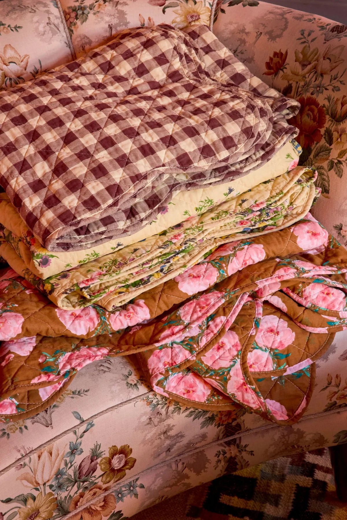 Stack of floral and checkered quilts on a floral-patterned surface