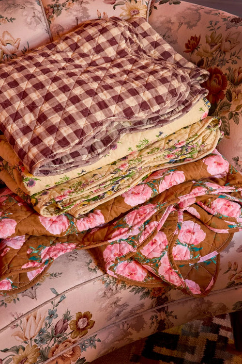 Stack of floral and checkered quilts on a floral-patterned surface