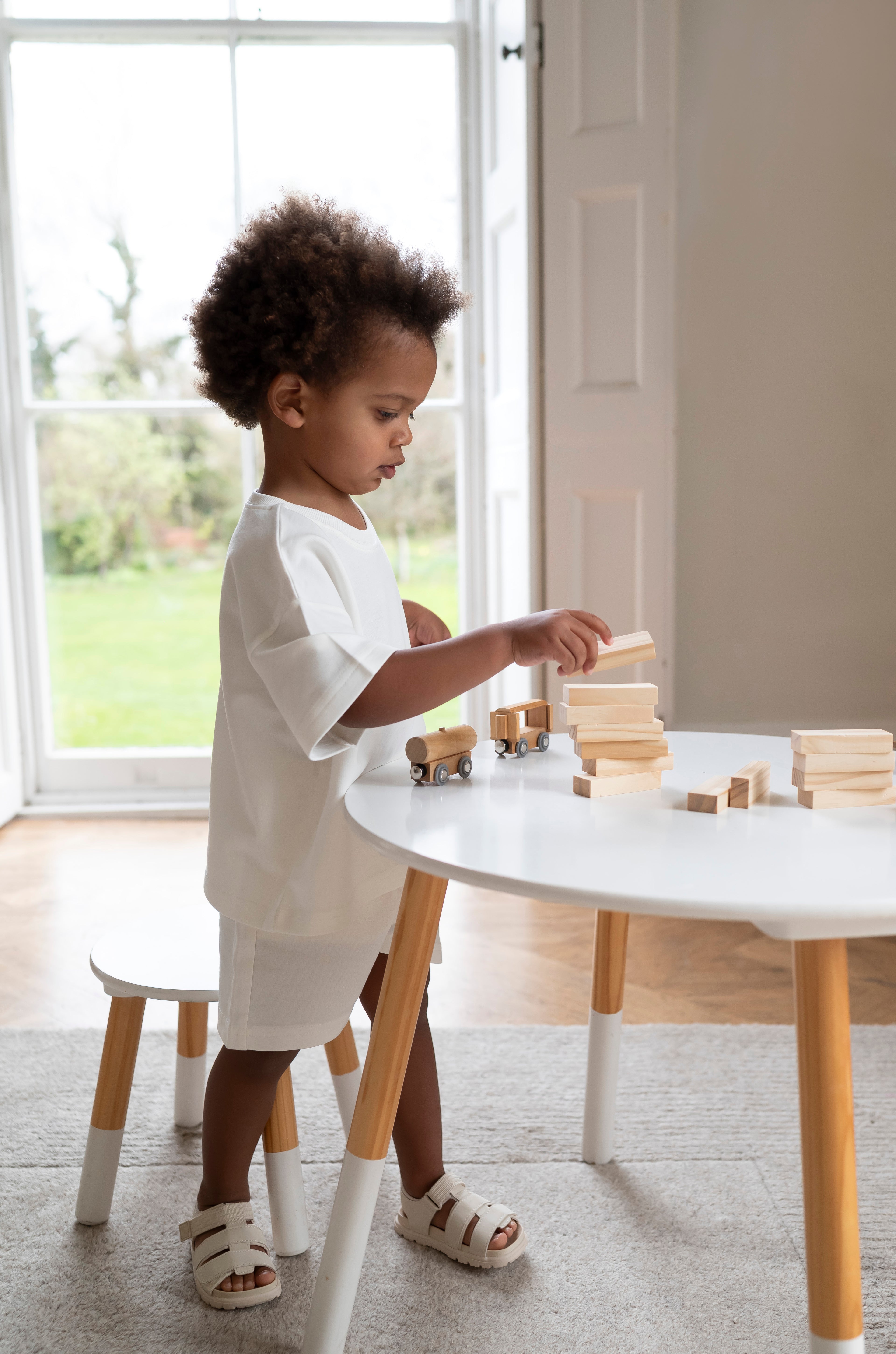 Child playing with wooden blocks at a table in a bright room