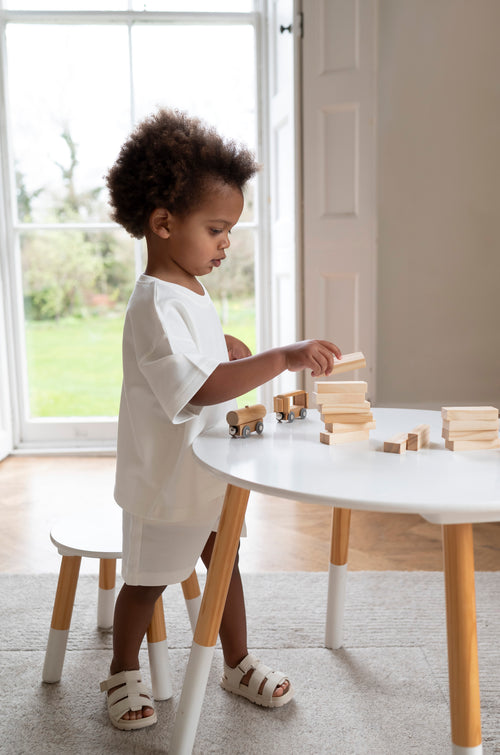 Child playing with wooden blocks at a table in a bright room