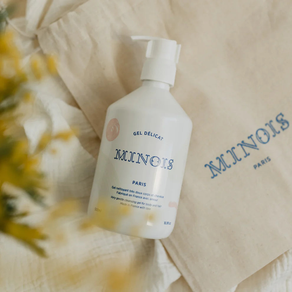 White bottle with pump and beige towel branded 'MINOIS PARIS' on a soft background