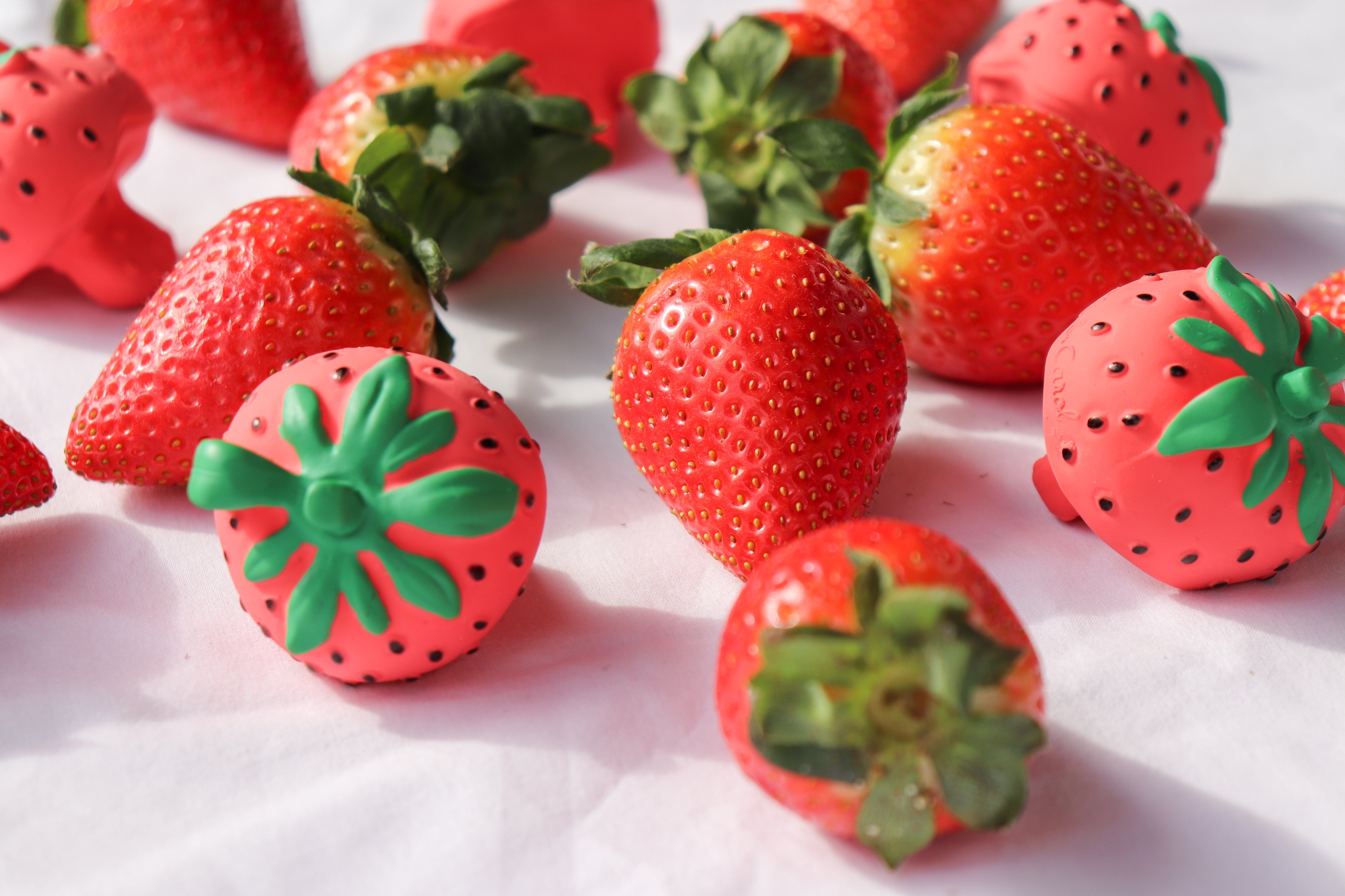 Strawberries with green leaves on a white surface