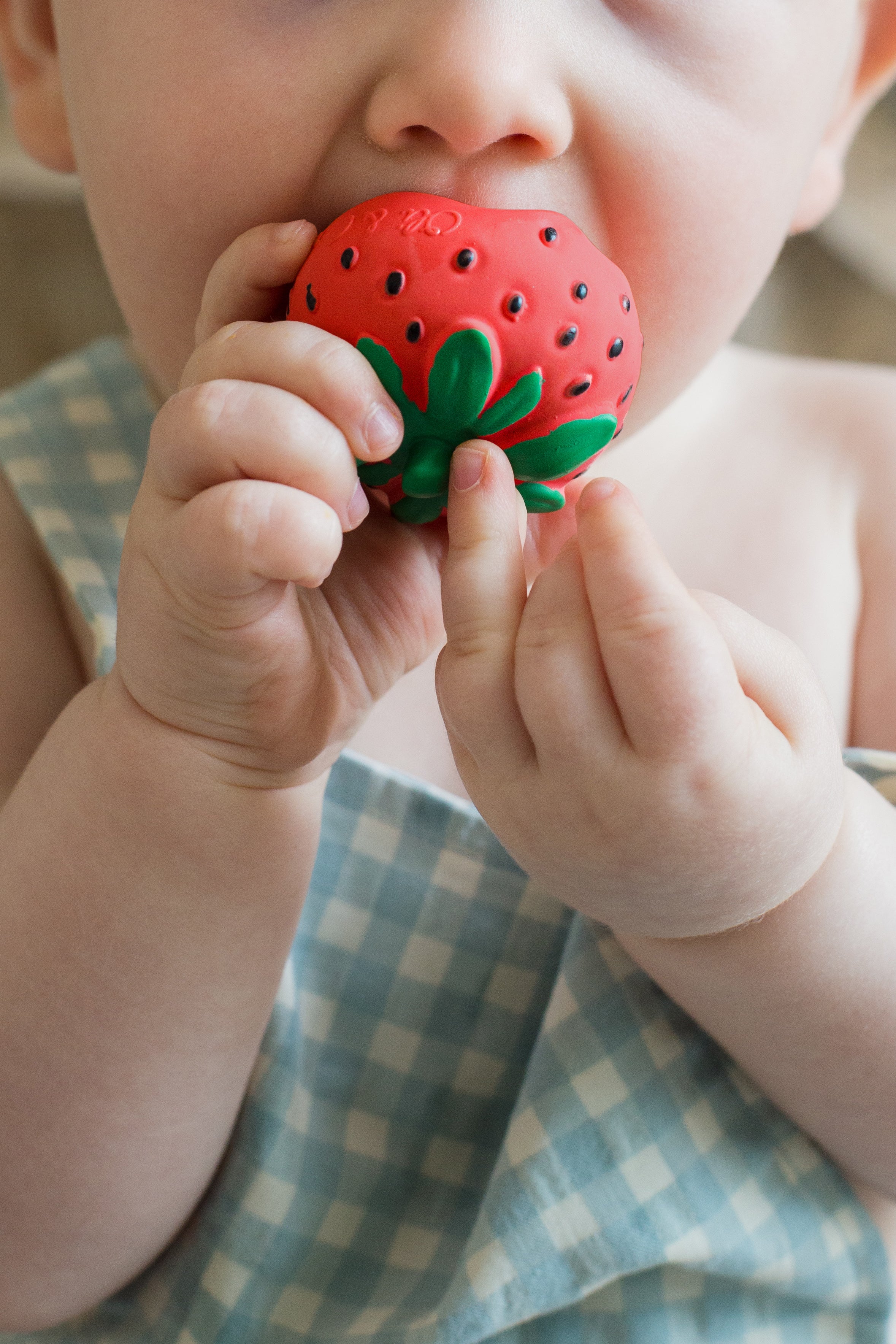 Baby holding a red strawberry-shaped teether