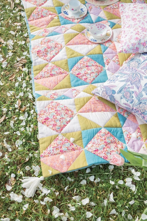 Quilt with floral patterns on grass