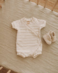 Baby romper and booties on a wooden crib