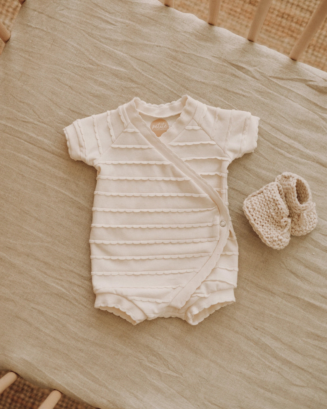Baby romper and booties on a wooden crib