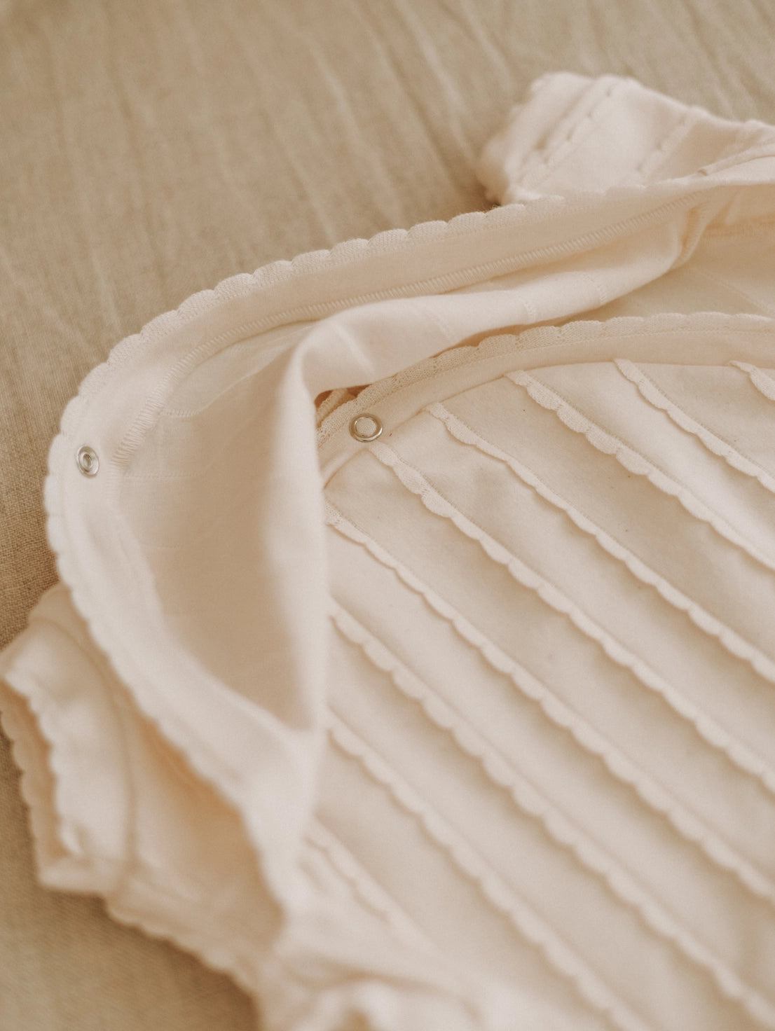 Close-up of a beige textured fabric with pleated details on a beige background