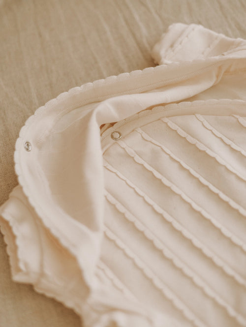 Close-up of a beige textured fabric with pleated details on a beige background