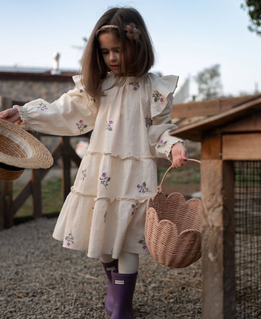 Young girl in a floral dress holding a basket outdoors
