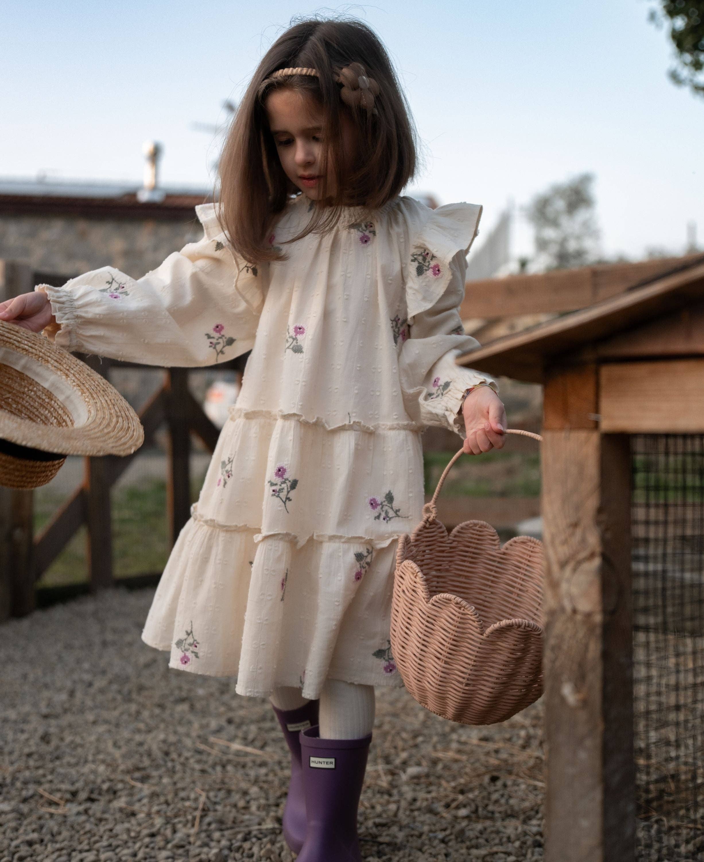 Young girl in a floral dress holding a basket outdoors