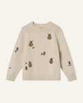 A cream-colored knit sweater featuring embroidered brown pineapples with green tops and leaves, displayed against a light gray background.