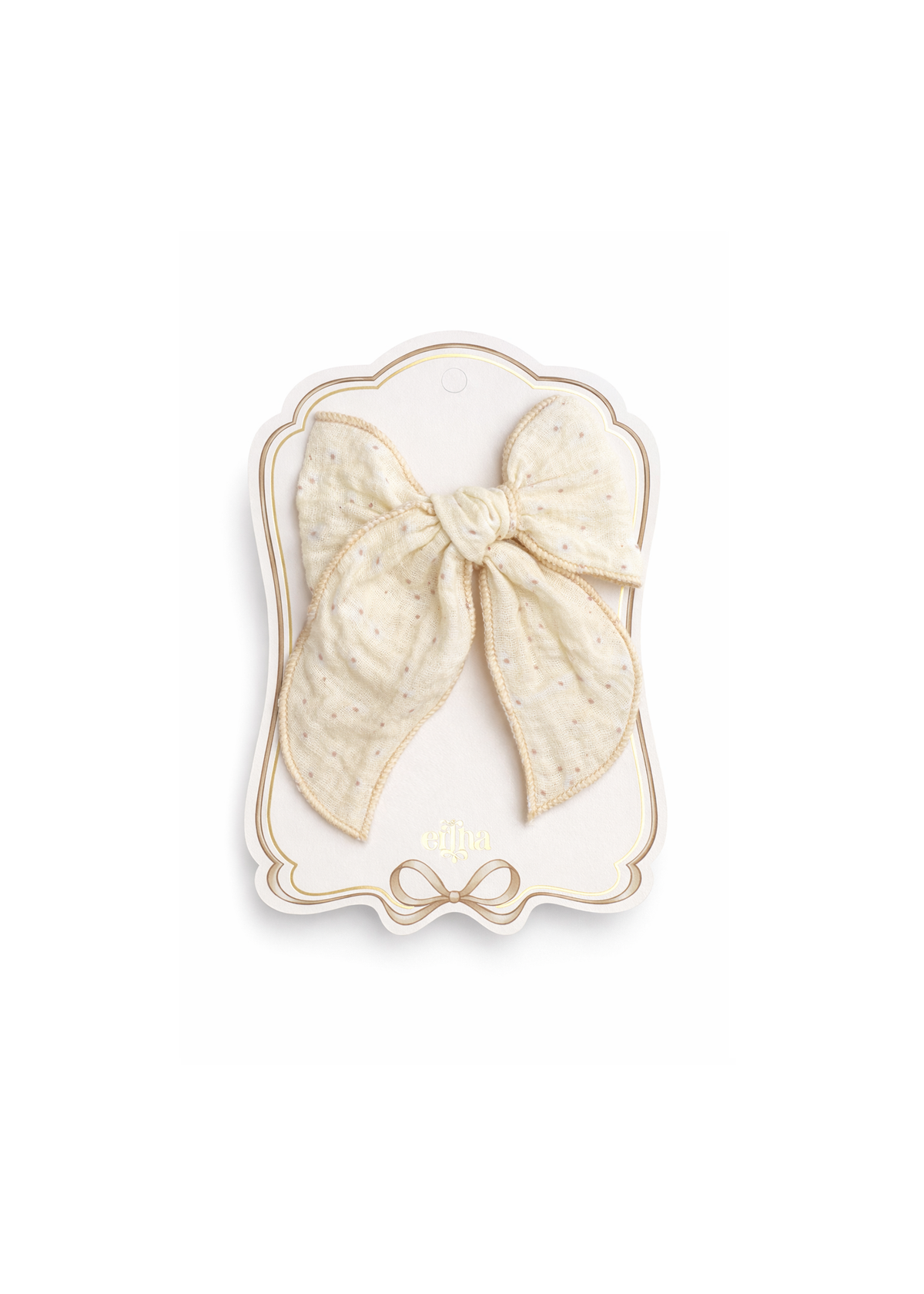 An off-white textured fabric hair bow with tiny gold speckles, attached to a decorative cream-colored display card with gold trim.