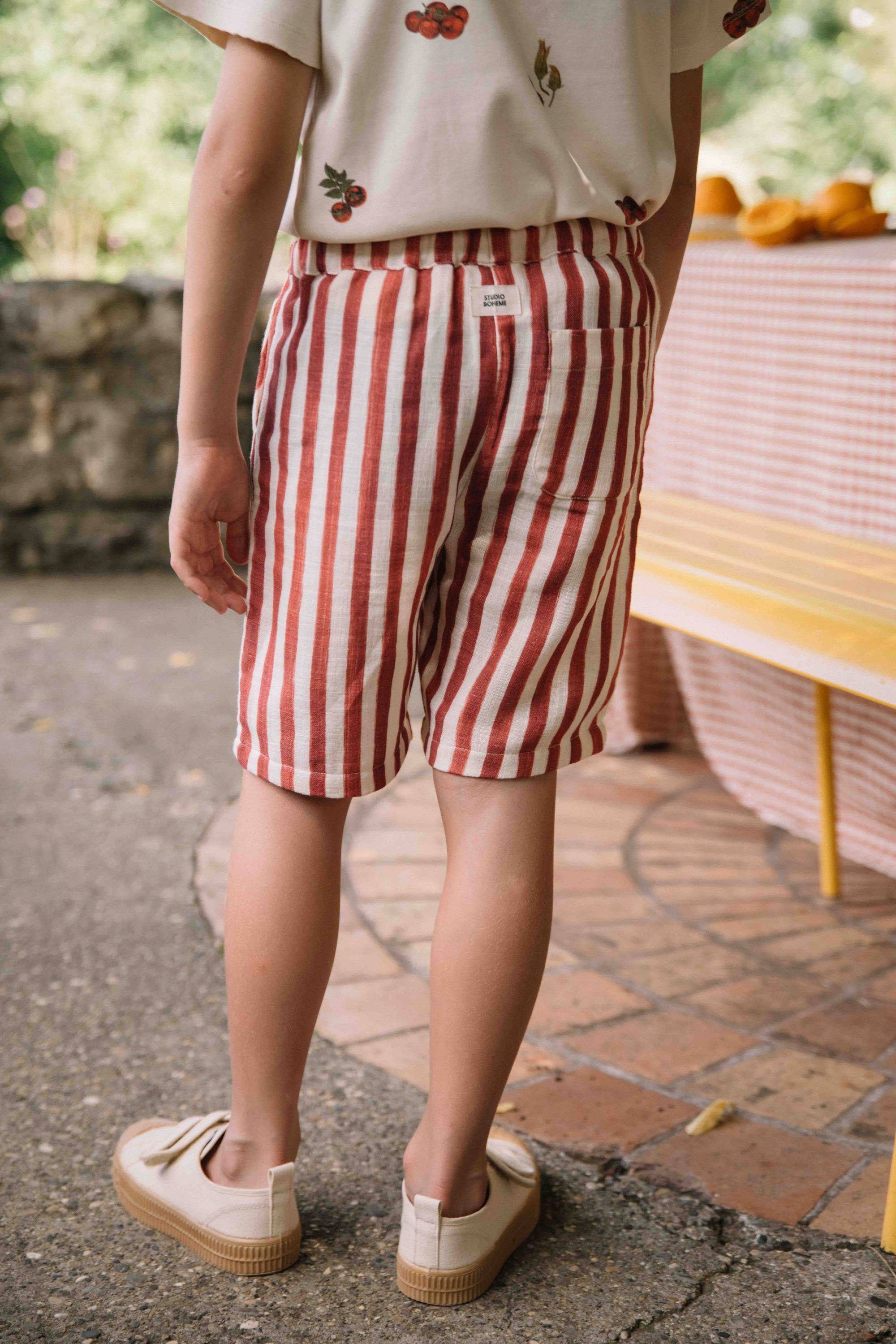 Person wearing red and white striped shorts standing outdoors.