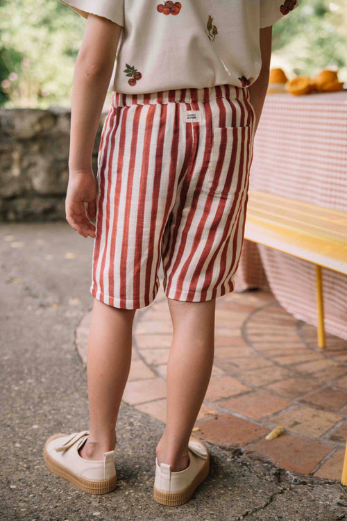 Person wearing red and white striped shorts standing outdoors.