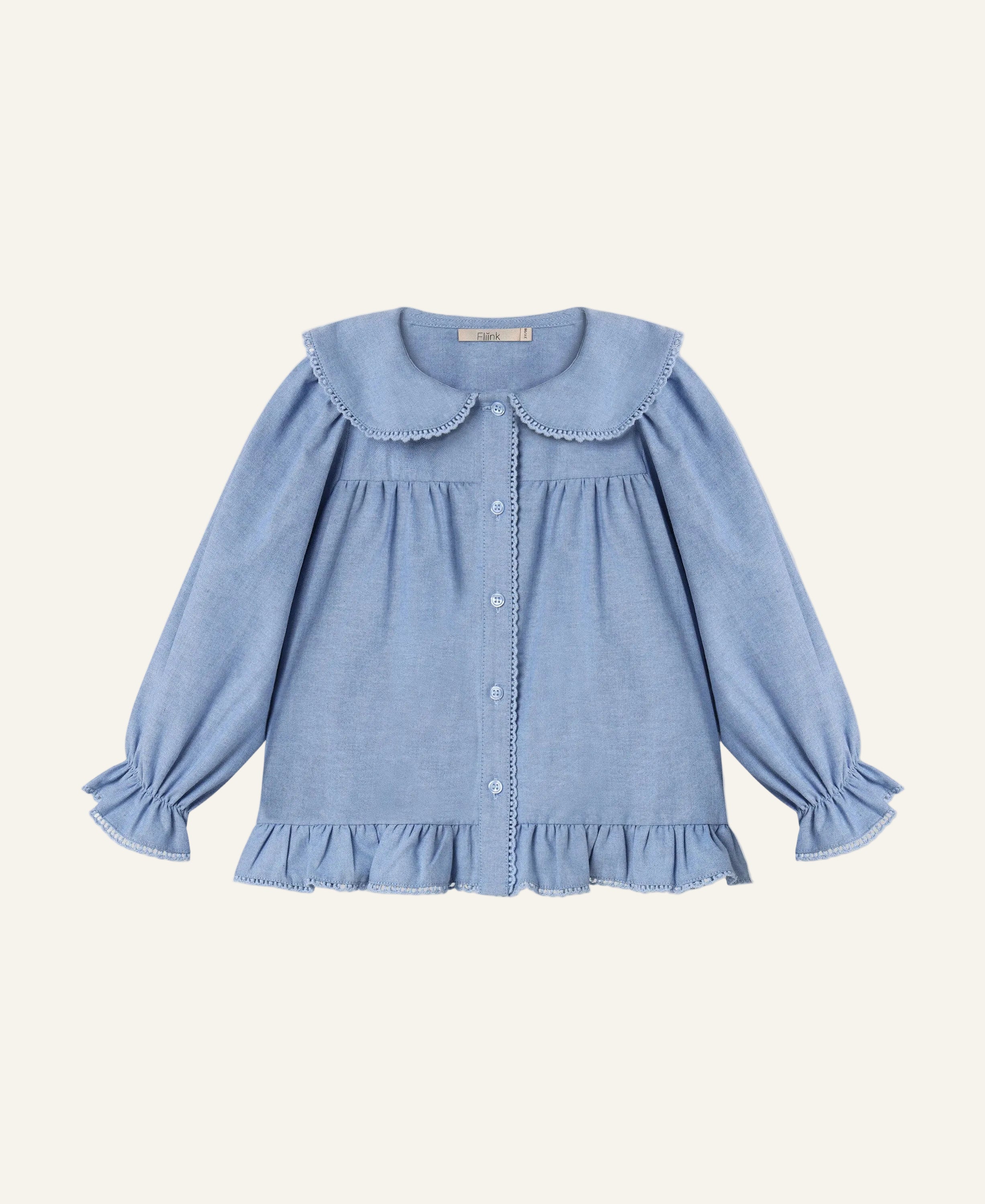 A light blue long-sleeve blouse for toddlers, featuring a large Peter Pan collar, button-up front, and ruffled trim at the hem and cuffs, shown flat on a light gray background.